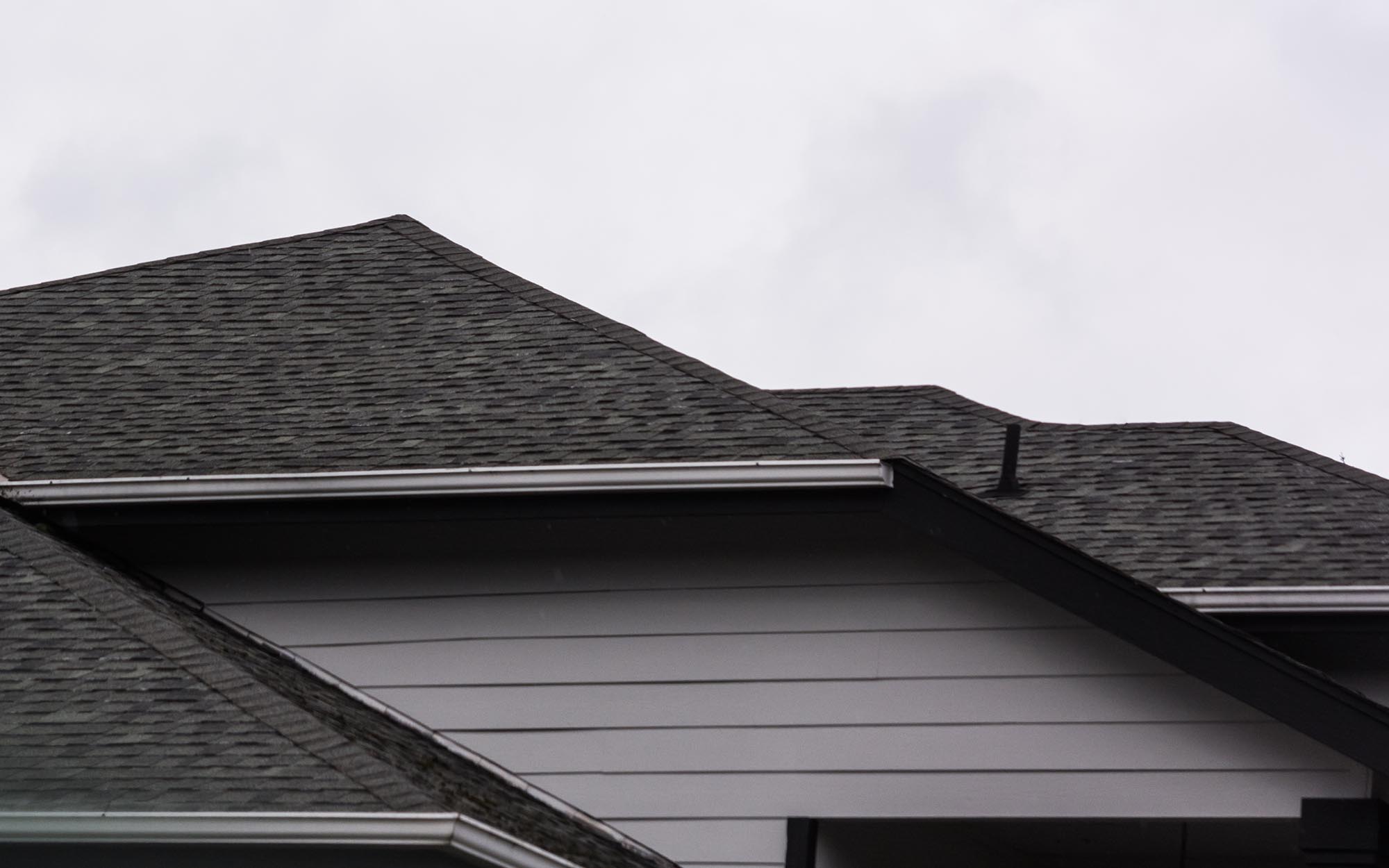 Side View Of A House With Dark Grey Aphalt Shingle Roofing And Grey Siding