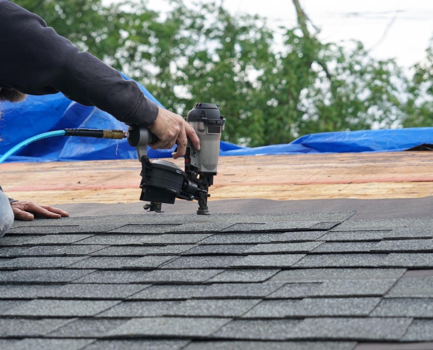 Side View Of A Man Nailing Shingles To A Roof Copy